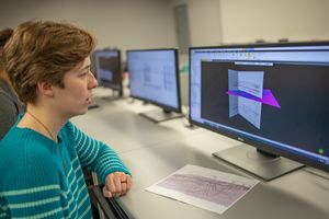 Female student faces a monitor displaying technical geology images