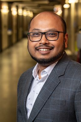 Subhasish Mandal, WVU assistant professor in condensed matter physics, wears a plaid suit jacket, white button down dress shirt, dark plastic framed glasses. He has a dark, trimmed mustache and beard.