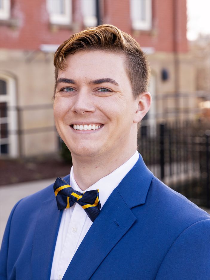 Zackery Dean wearing a bright blue suit jacket with a striped dark blue and gold bowtie