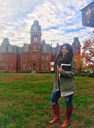 Amelia Jones holding a coffee in front of Woodburn Hall