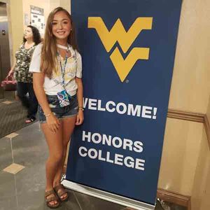 Maggie Robertson in front of Welcome to Honors College banner