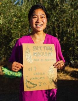 Woman holding a sign that says "bitter melon"
