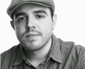 Black and white photo of poet José Olivarez wearing a hat