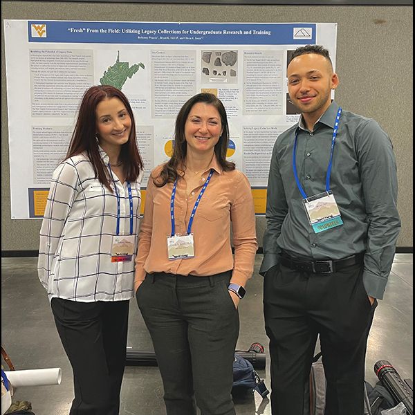 Bethany stands with two other students in front of a research poster