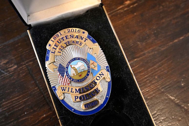 Nolan's police badge displayed in a special box on a wood table. 